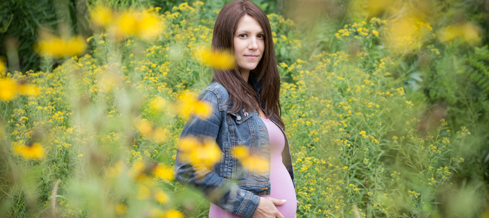 White pregnant woman in a field of yellow flowers
