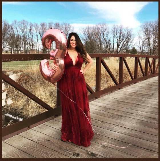 Mia in a red dress holding a large, pink "3" balloon