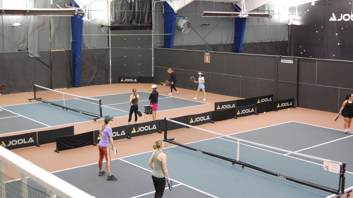 Women playing pickleball at an indoor court
