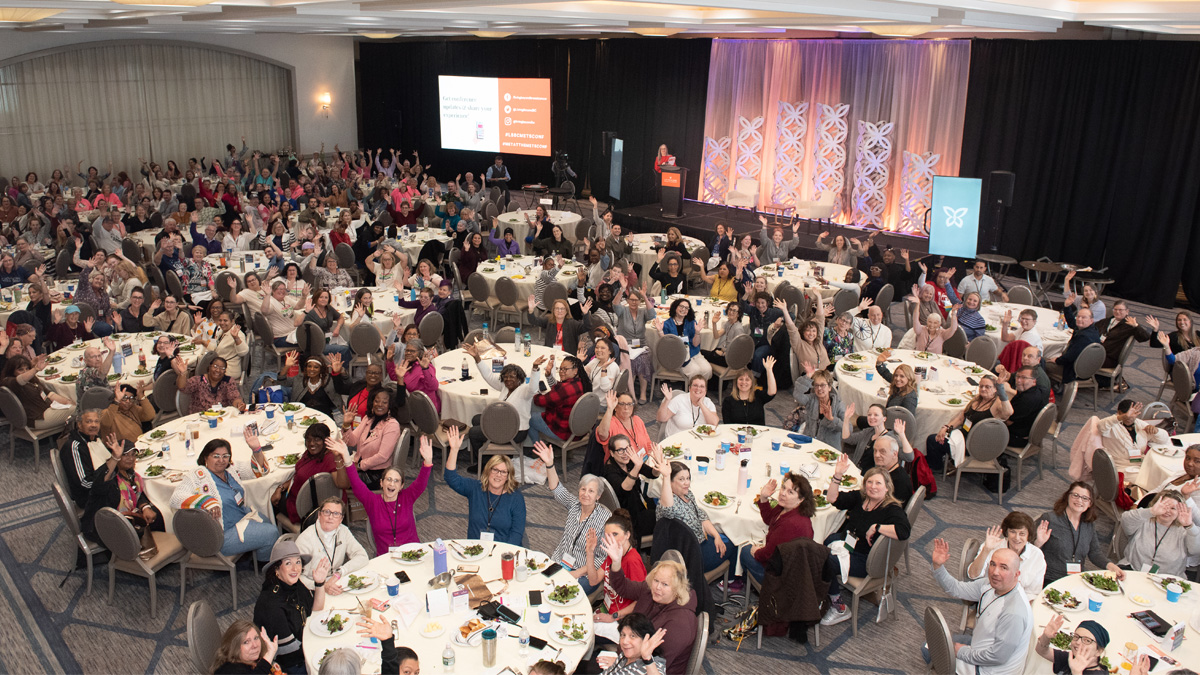 Hundreds of 2025 Mets Conference attendees sitting at tables waving