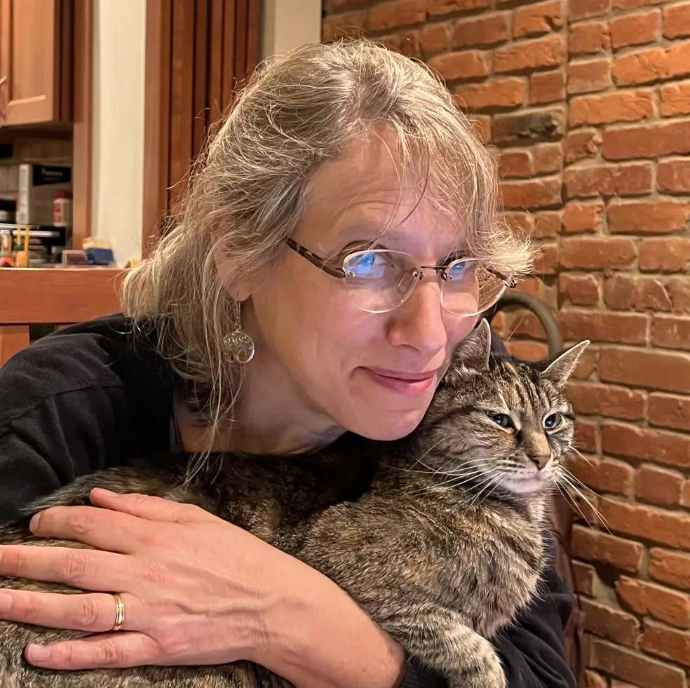 Kate, a white woman with glasses, holding her cat