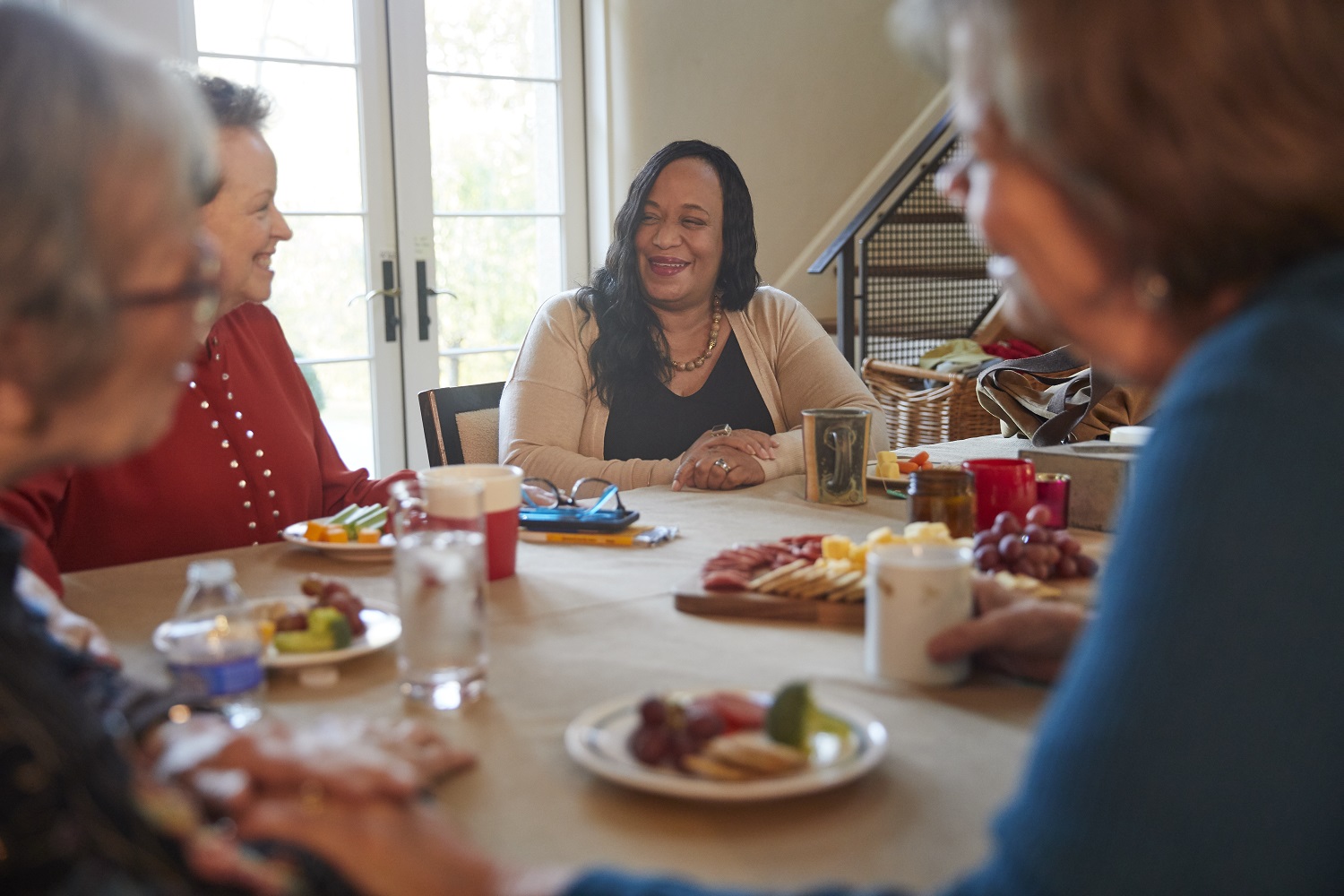 Group of women sitting arond a table sharing laughs and support