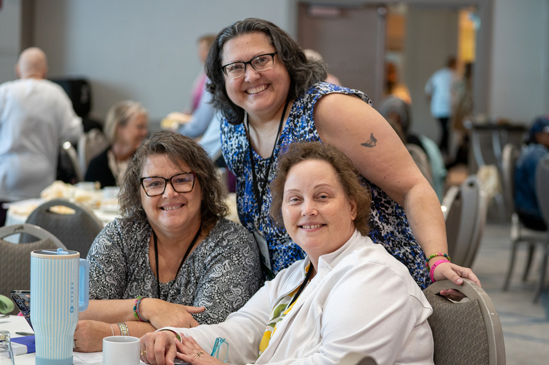 Three older white women smiling at their table at the 2026 MBC conference