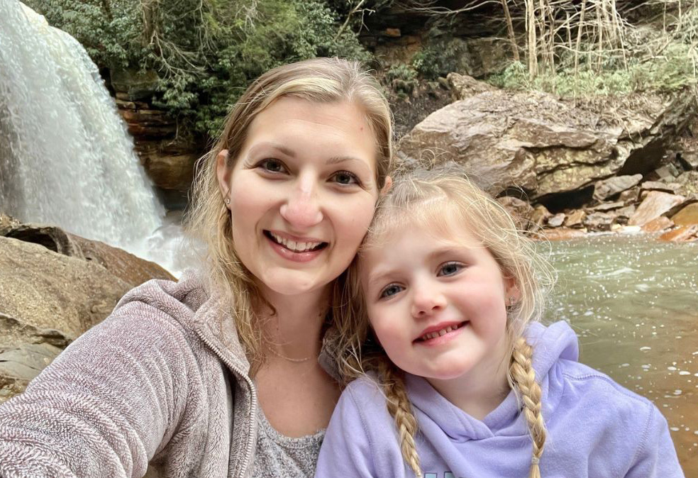 Kara Taylor and her daughter enjoy the beauty of nature together, a waterfall behind them.