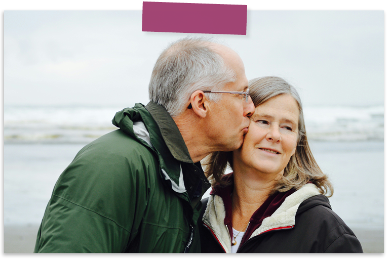 An elderly white man kissing his white wife's cheek