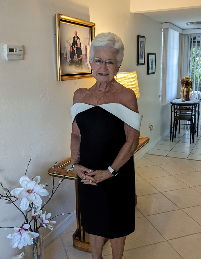 Myra smiling in her house in a black and white dress