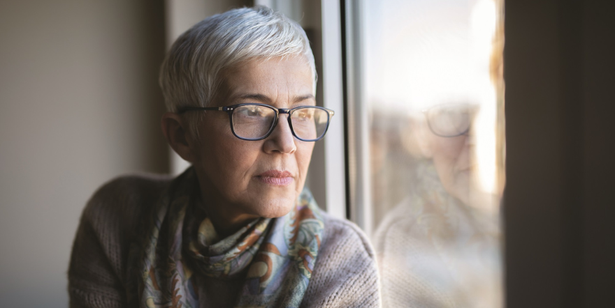 Older white woman looking pensively out window