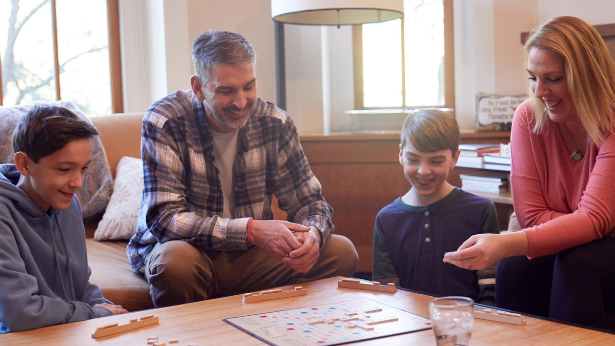 A white family laughing and playing scrabble