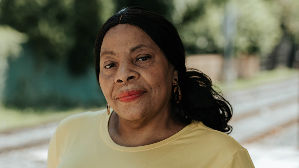 A Black woman standing in an empty trolley station, looking into the camera.