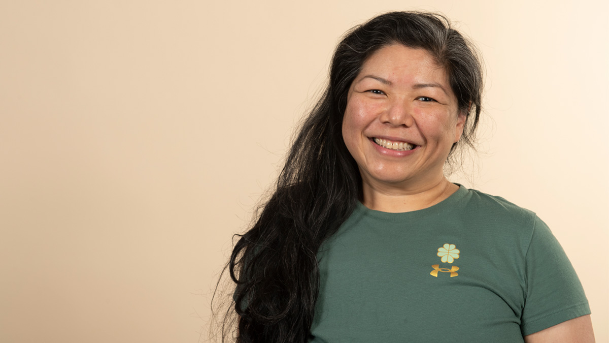 An Asian woman smiling in front of a beige background