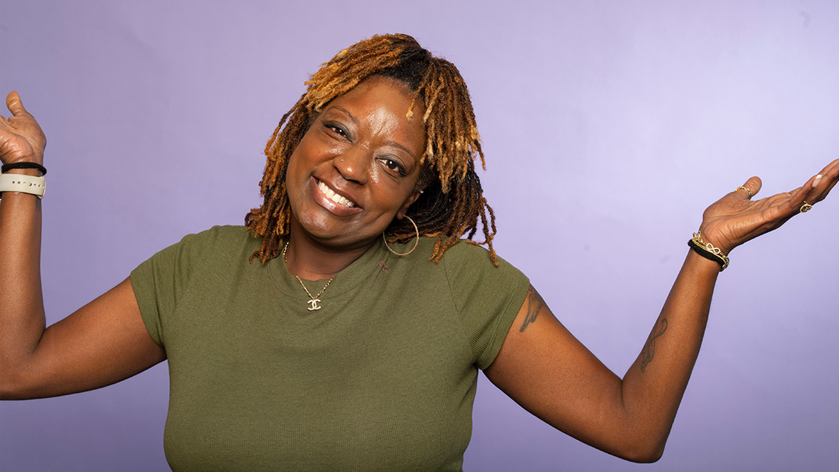 A Black woman smiling and shrugging her shoulders