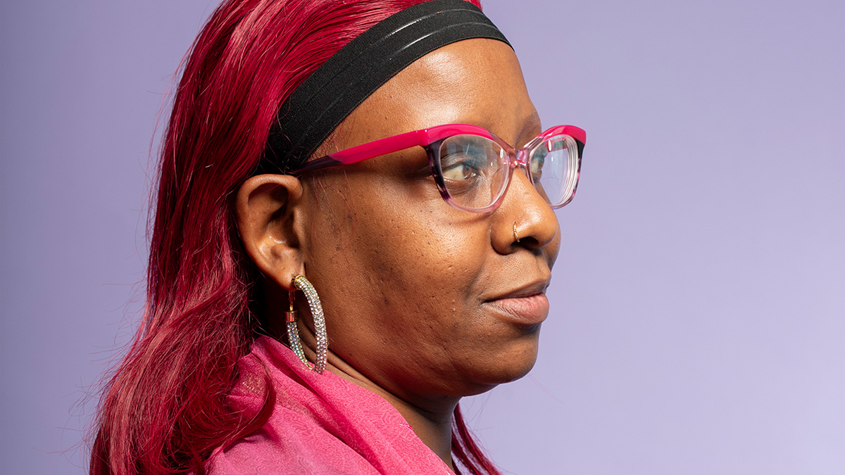 A Black woman with pink hair looking off into the distance