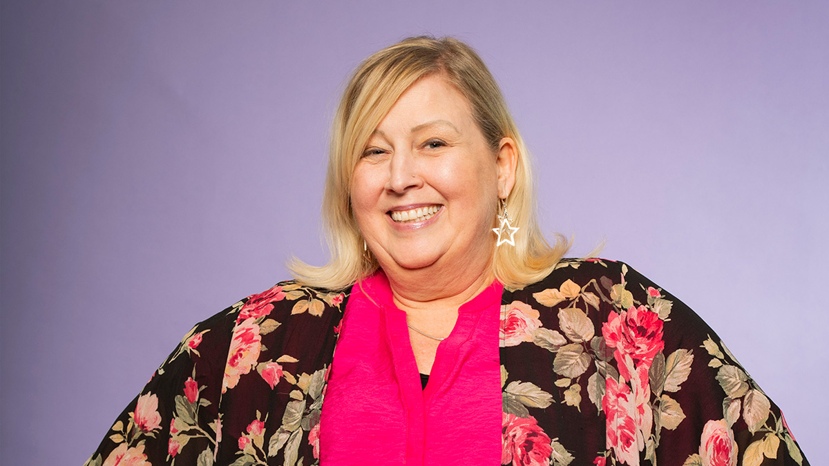 A larger white woman smiling, with her hands on her hips