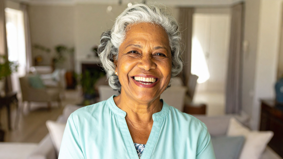 An older Black woman smiling inside her home