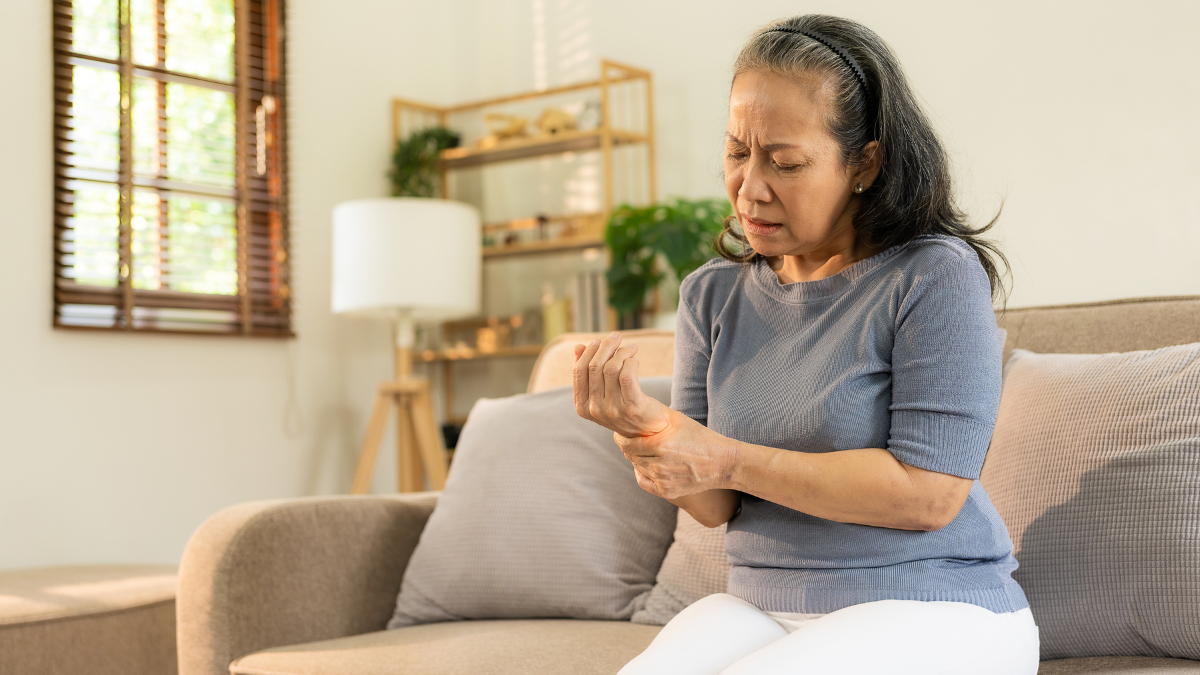 An older Asian woman holding her wrist in pain