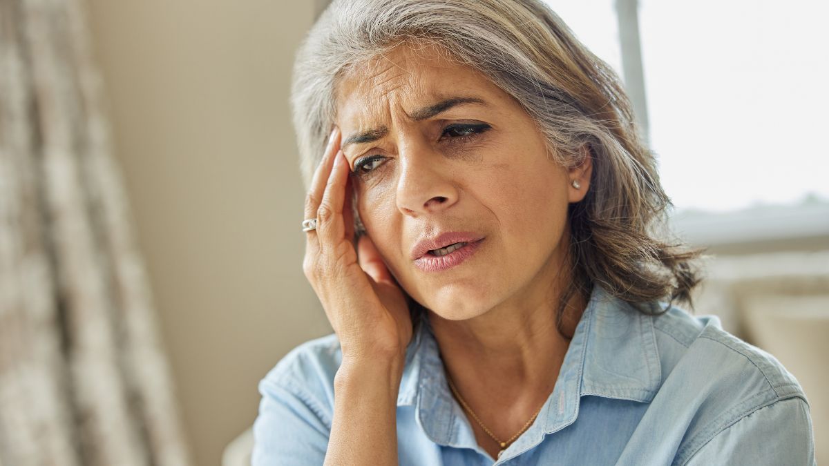 An Indian woman touching her hand to her head in pain