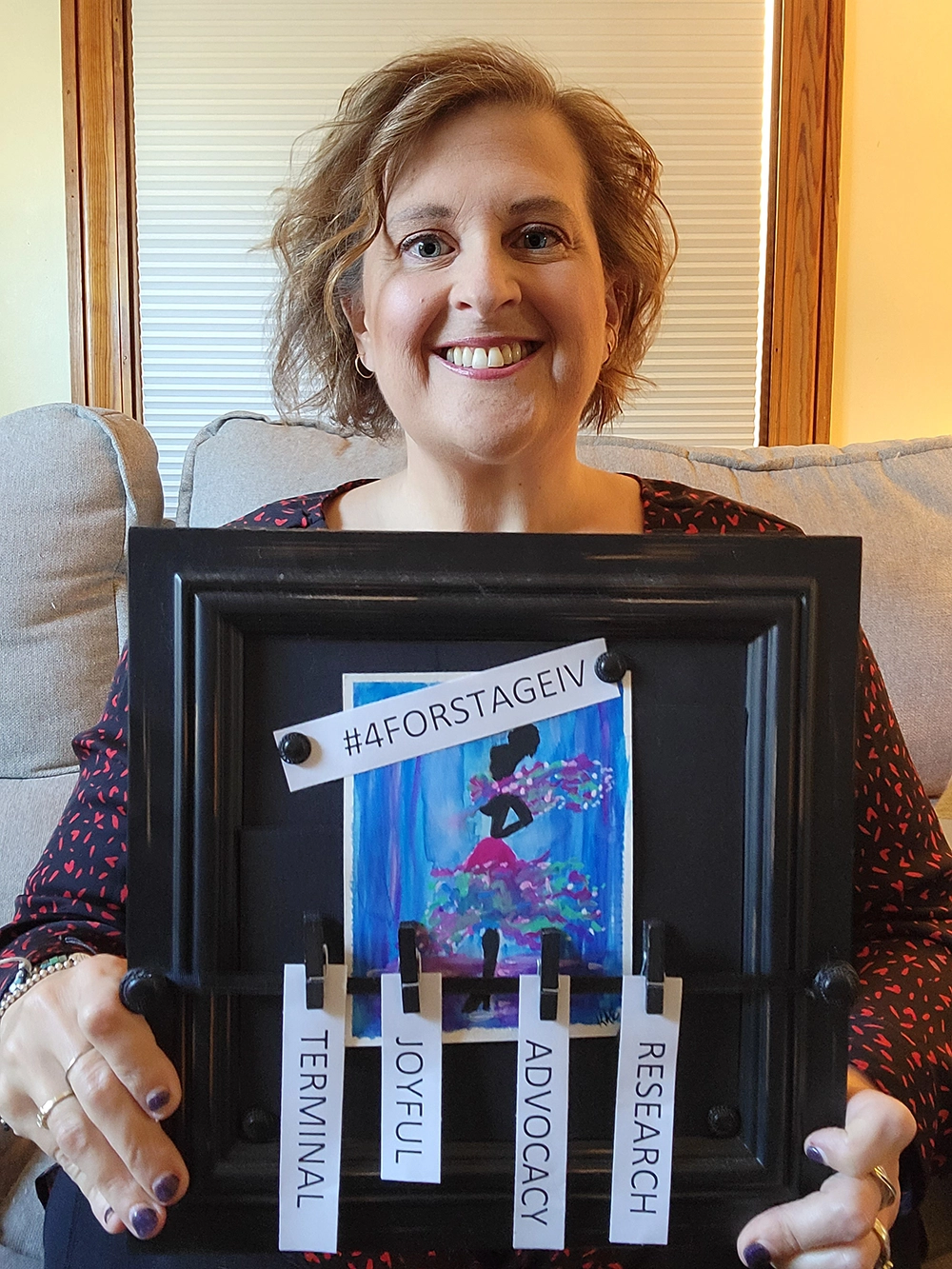 White woman holding framed artwork with the words Terminal, Joyful, Advocacy, and Research clipped on