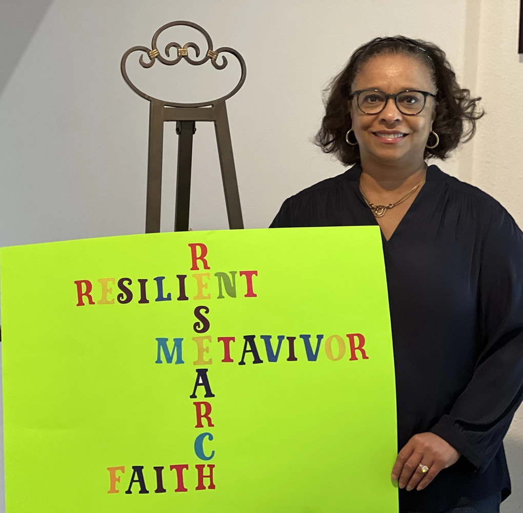 Black woman with neon green sign with the words Resilient, Research, Metavivor, and Faith spelled out in rainbow colors