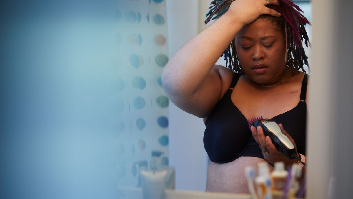 Distressed-woman in bathroom-with-electric razor