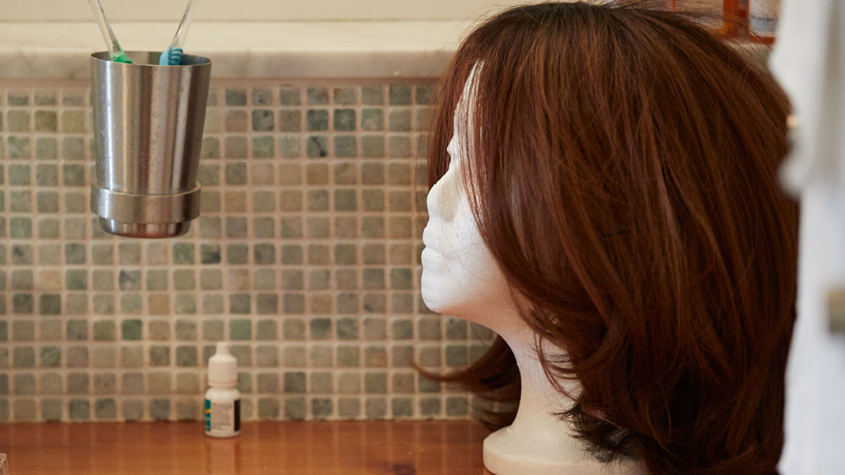 Brown wig on head form on bathroom counter