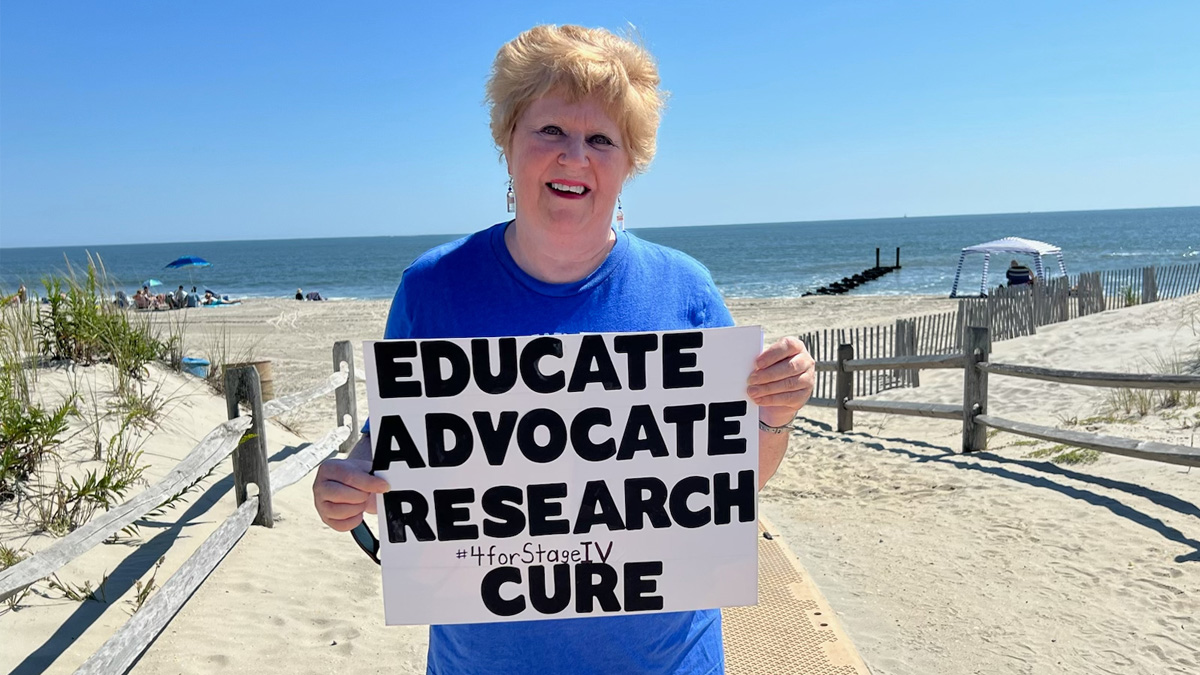 Jeanmarie holding a sign that says Educate, Advocate, Research, Cure