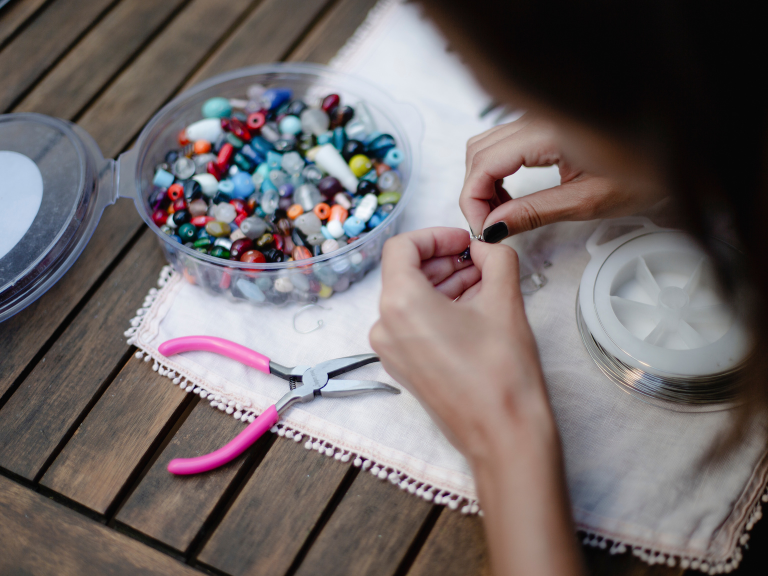 close-up of hands making beaded jewelry