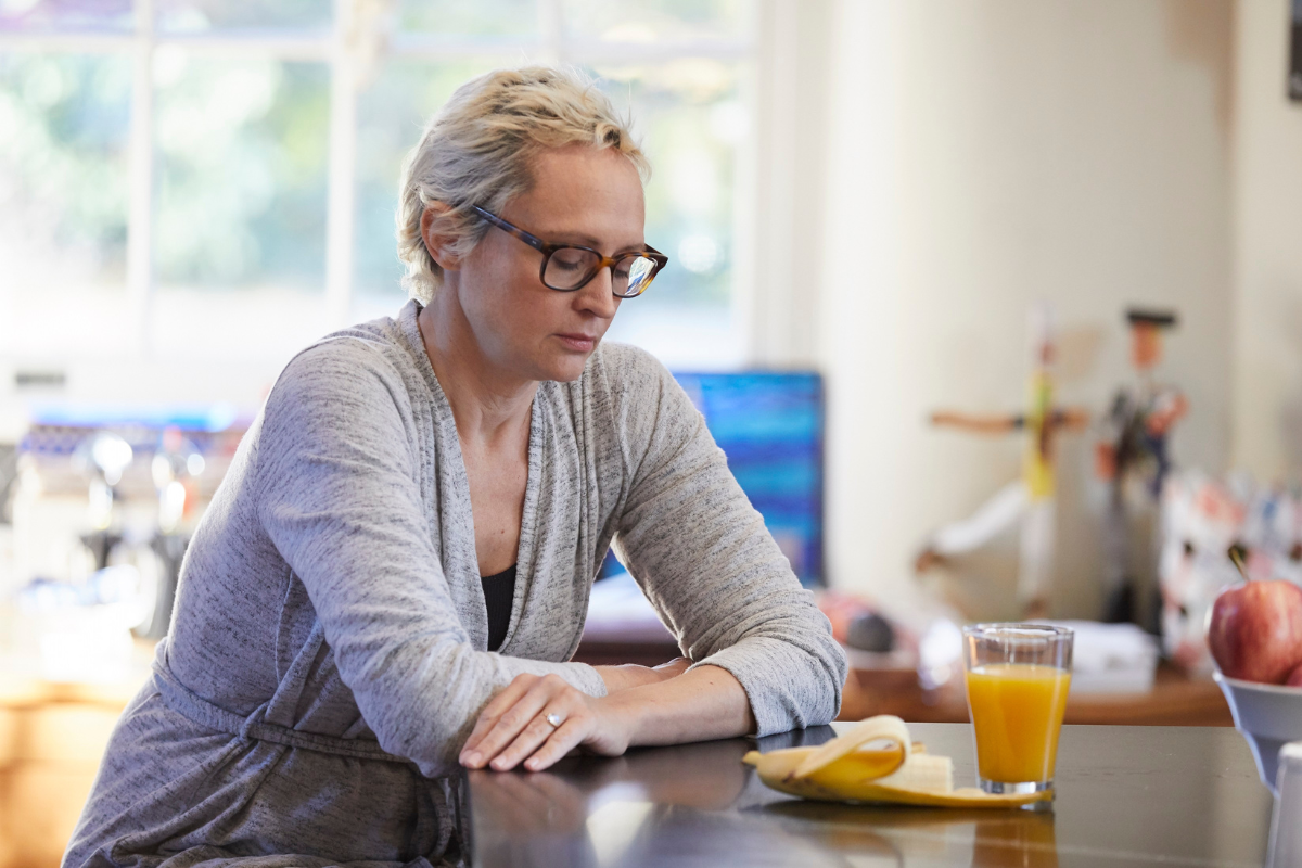 A woman looking somberly at her breakfast