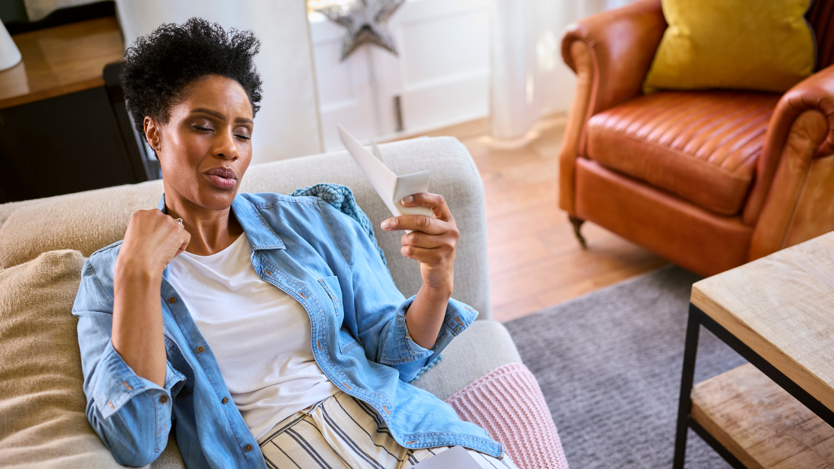 A Black woman fanning herself on the couch