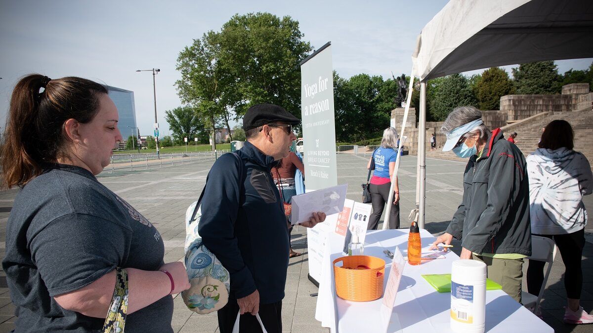A white woman and man standing in front of a table talking to a volunteer