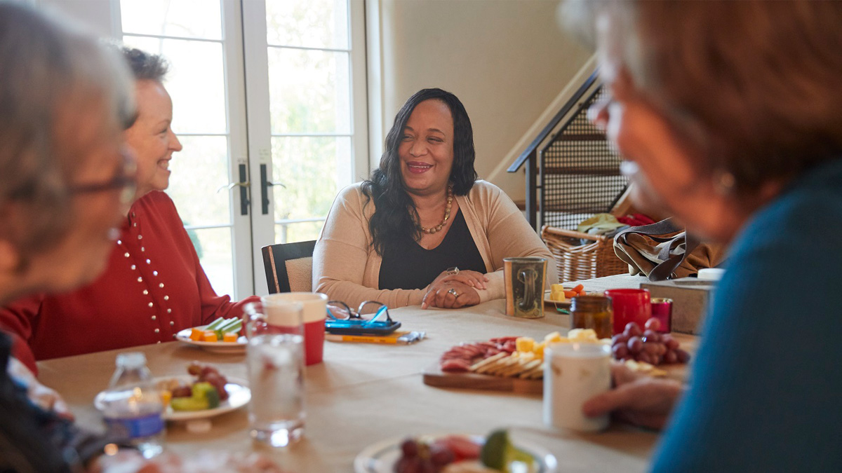 Group of women sitting around a table sharing laughs and support