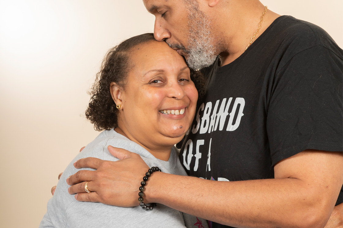 An older Black man holds his wife tenderly as she smiles
