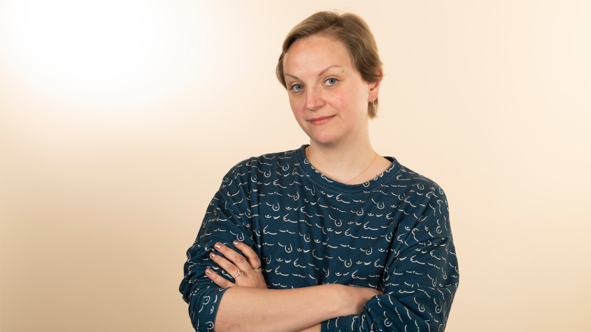 A white woman with her arms crossed looking pensive