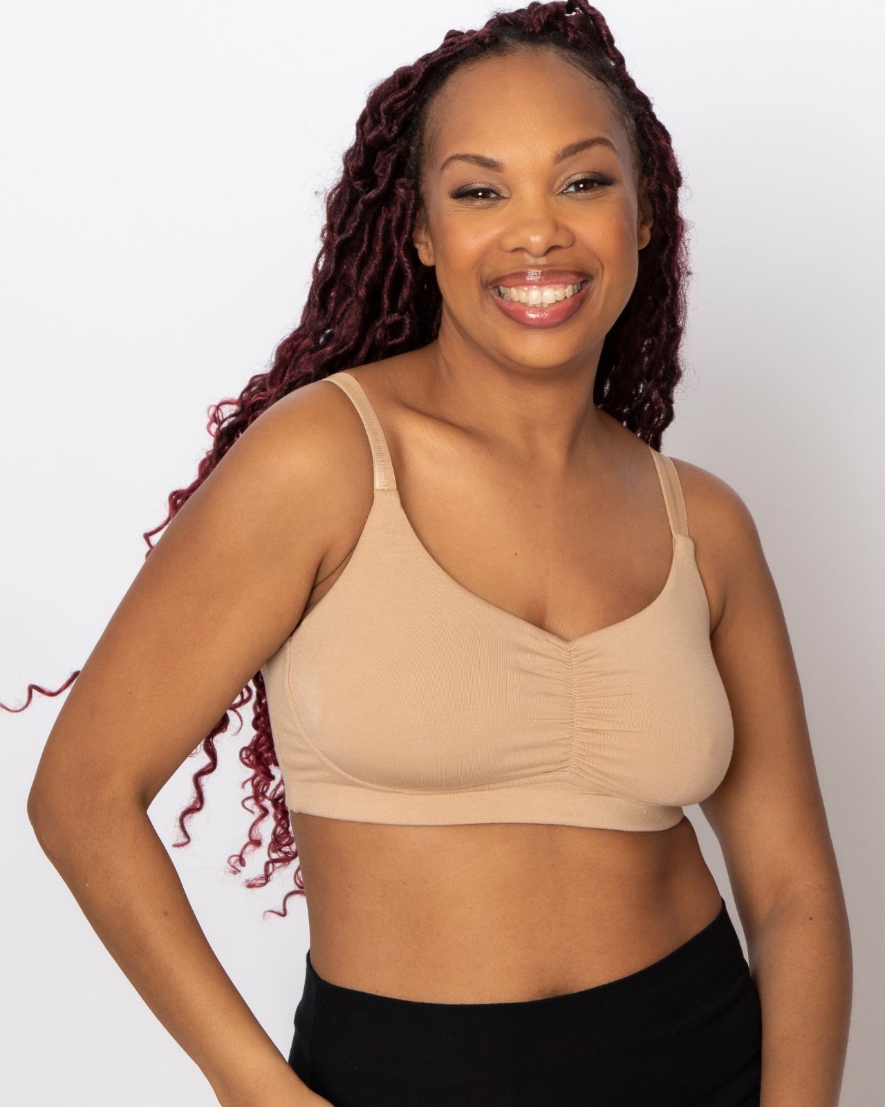 Black woman smiling and wearing a tan colored bra