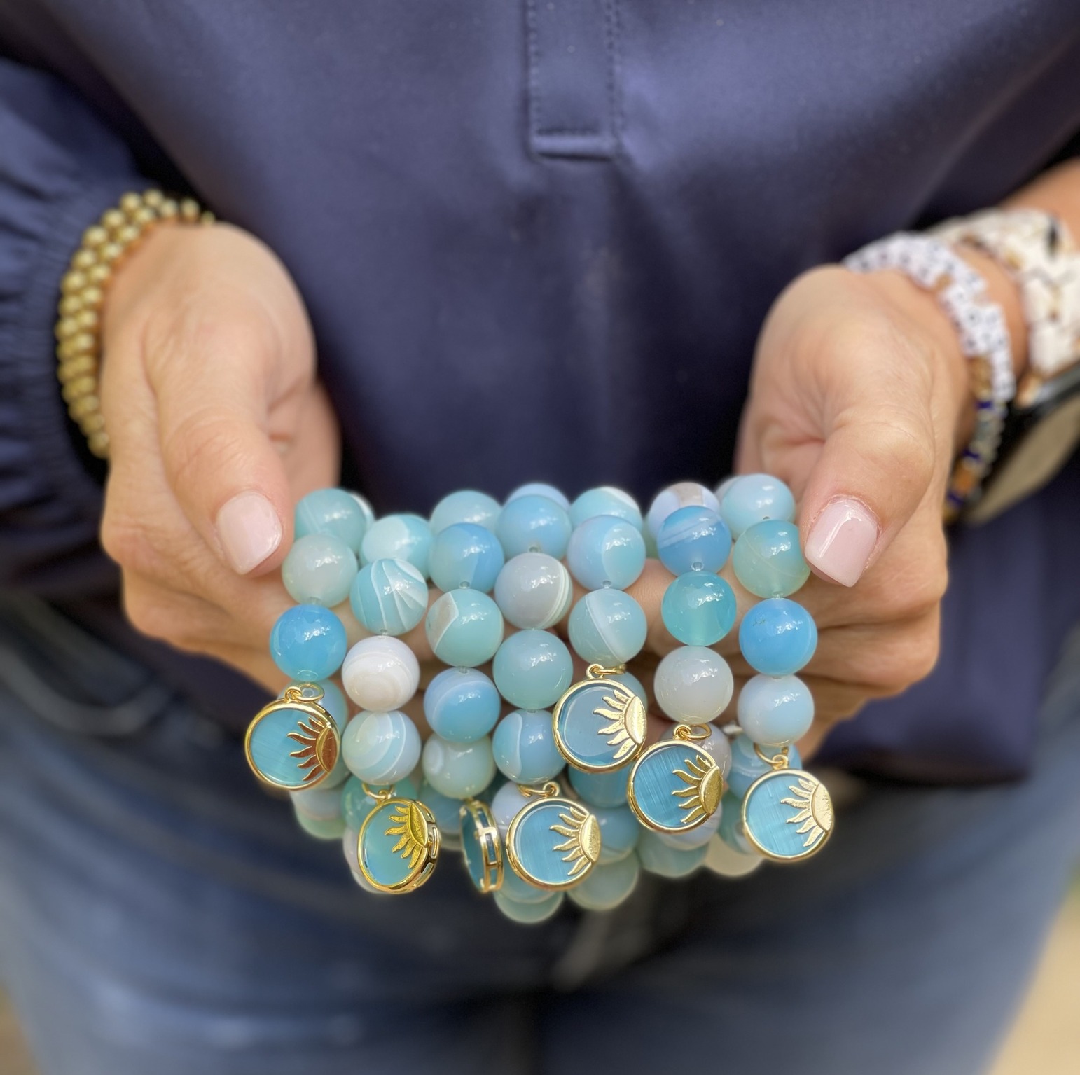 hands holding a stack of blue beads/bracelets