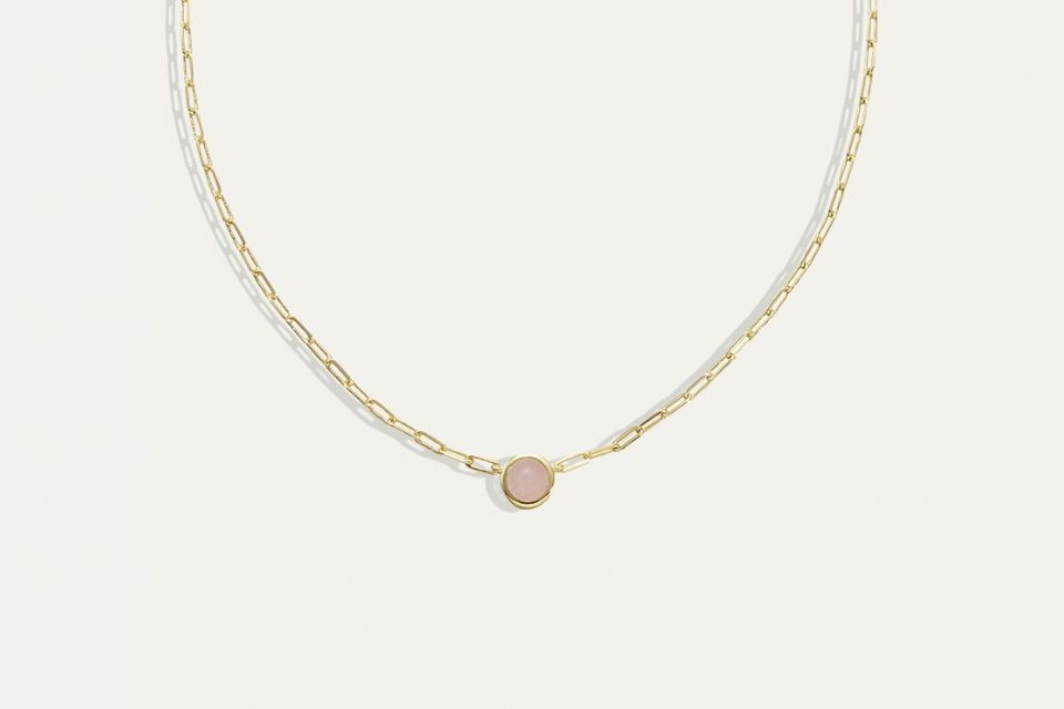 A gold necklace with one pink stone