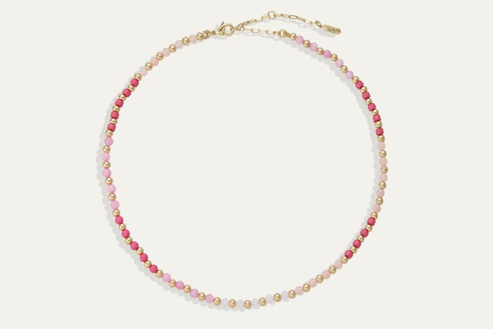 A gold necklace with pink beads