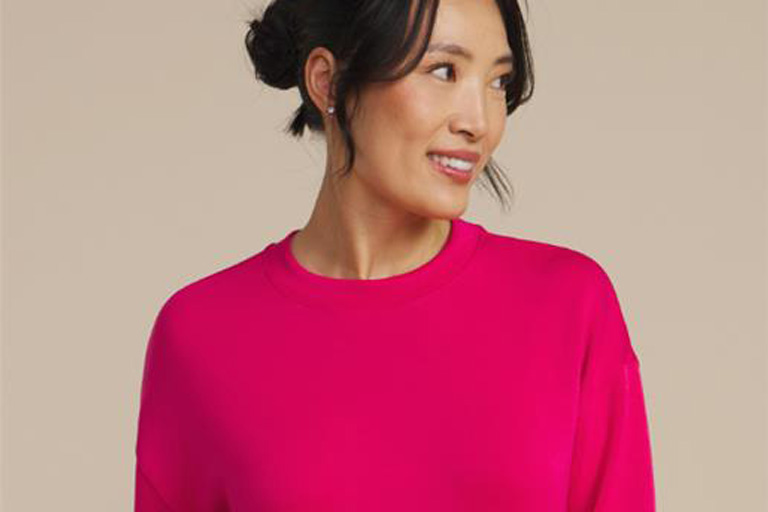 An Asian woman wearing a pink crewneck sweatshirt