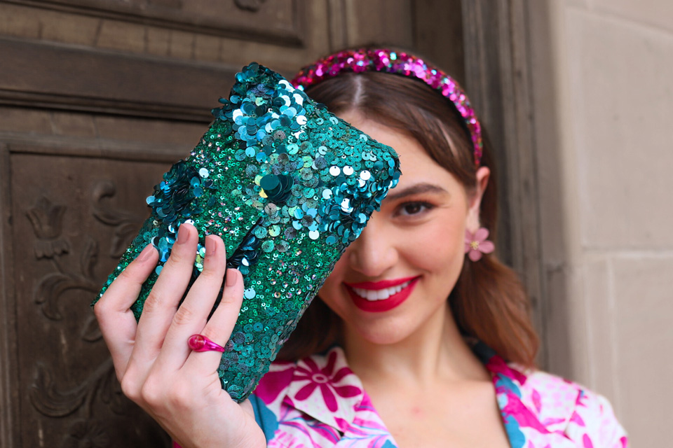 A woman holding a blue sparkly purse