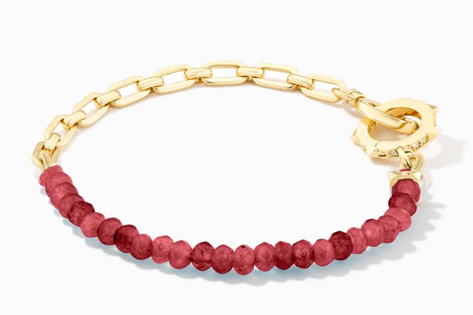 A gold bracelet with dark pink beads