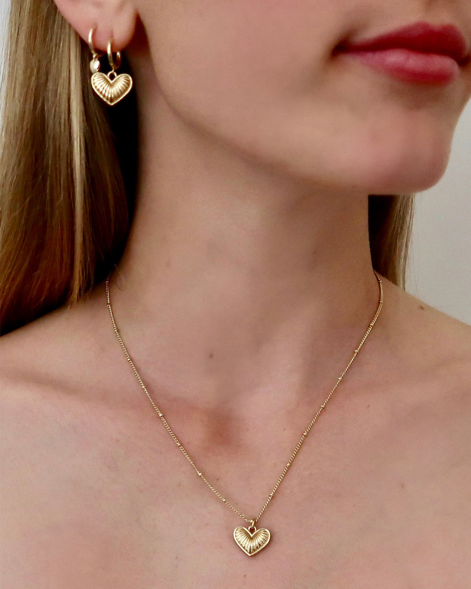 A woman modeling gold earring and a gold necklace