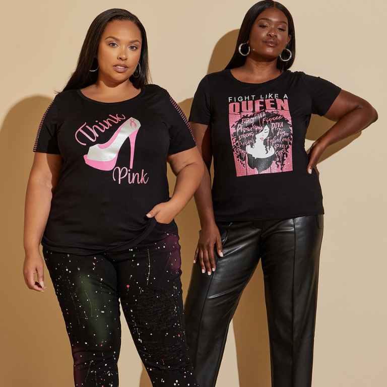 two women posing wearing black shirts that have pink/silver graphics on them