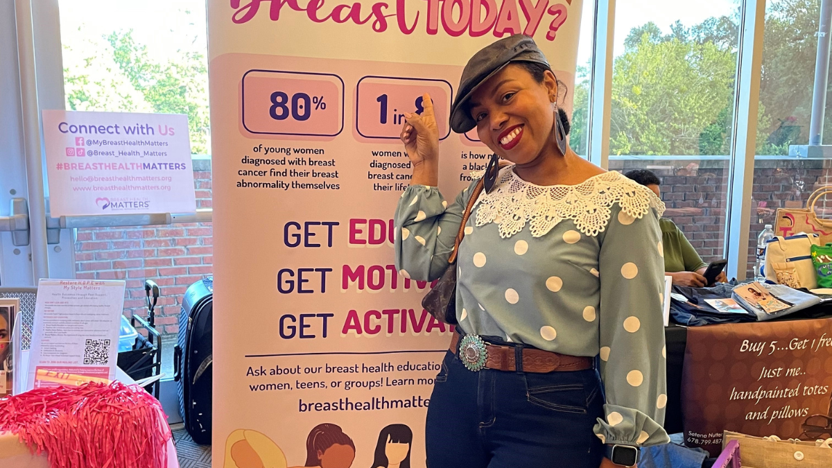 Patrice Exantus in front of breast cancer poster