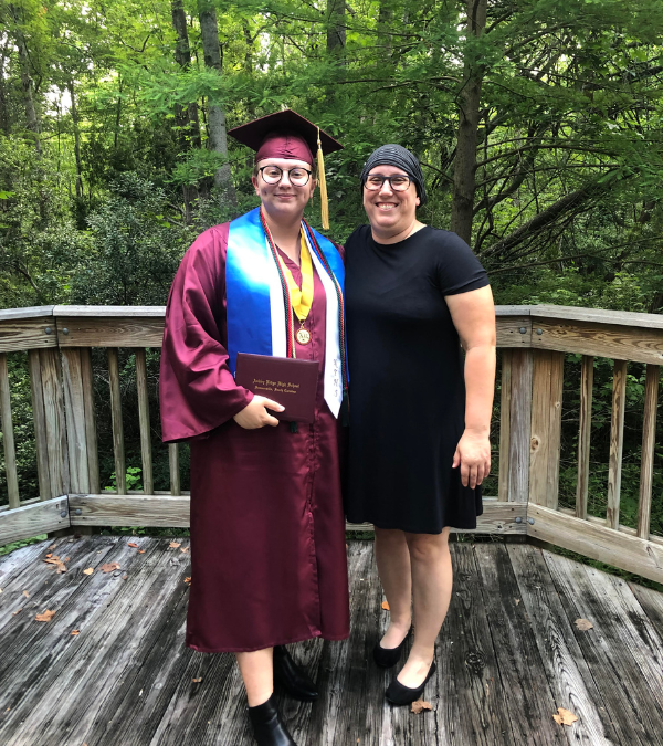 Emily in her graduation gown holding her high school diploma, with her mom