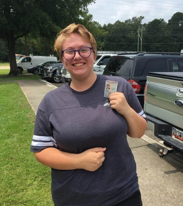 Emily smiling while showing off her driver's license