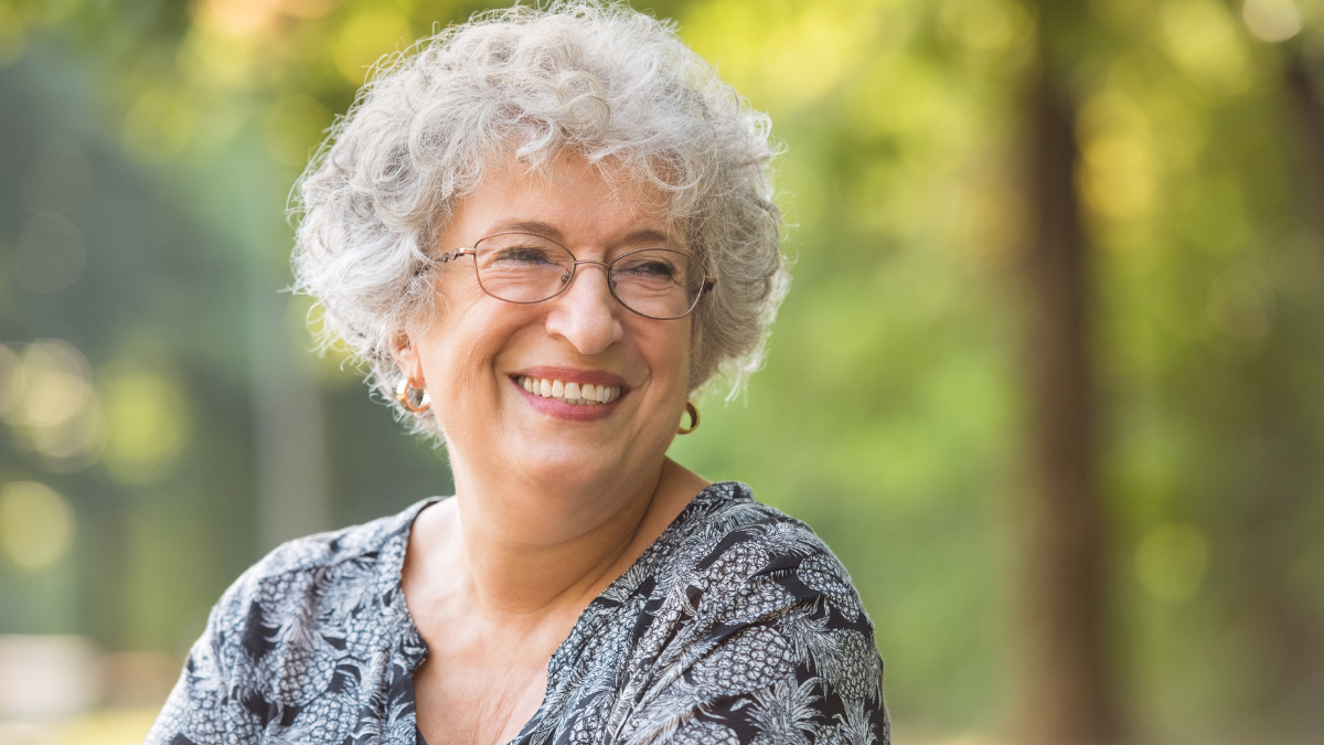 An elderly white woman smiling outside