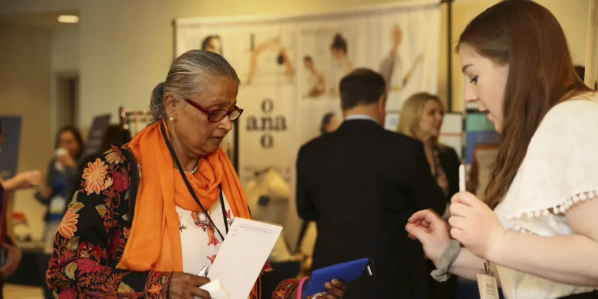 A woman talks to an exhibitor at the annual conference for metastatic breast cancer