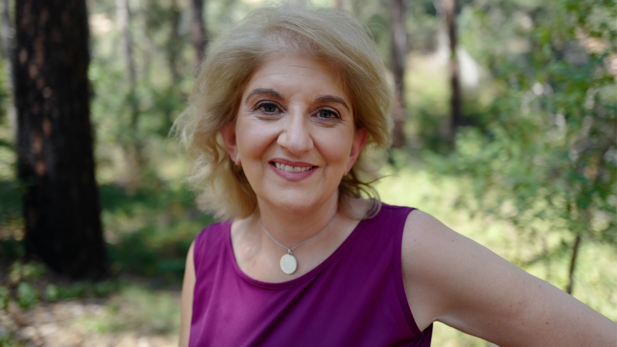 Portrait of Caroline with short blonde hair wearing a purple tank top.