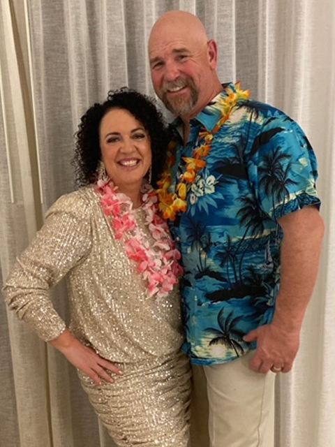 Heather and her partner, wearing leis