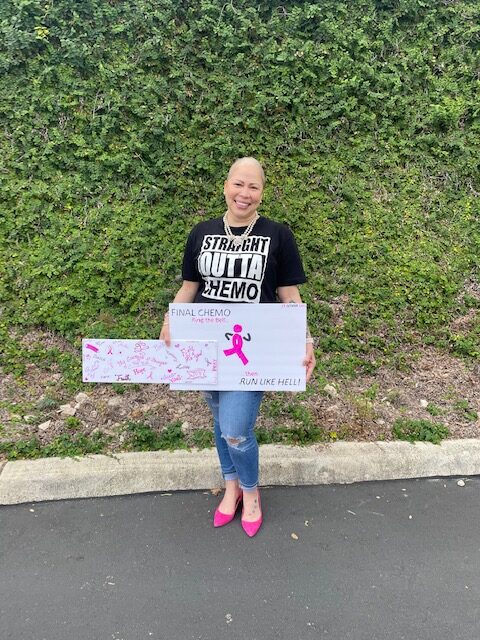 Nina wearing a "Straight Outta Chemo" shirt and holding a homemade "Final Chemo" sign with many signatures