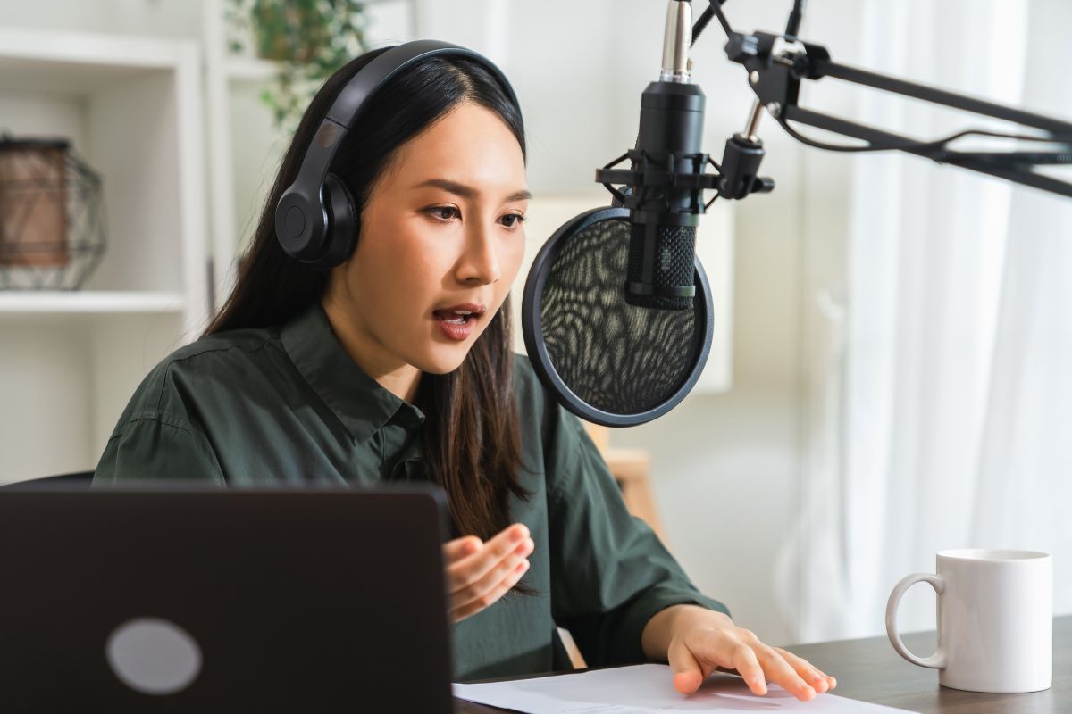 An Asian woman speaks into a professional microphone, recording a podcast